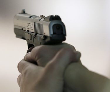 bărbat care trage cu pistolul